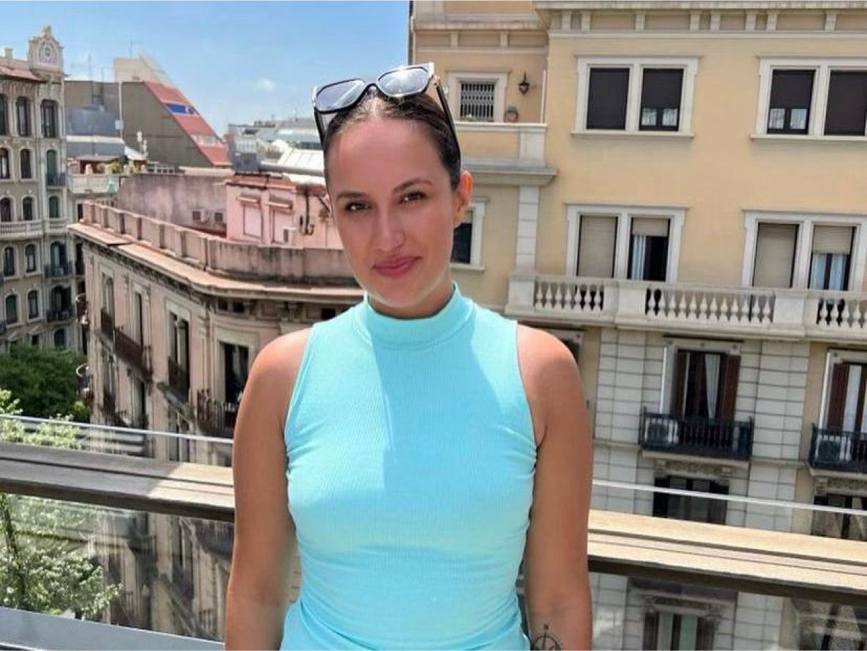 Danielle, a CLOUD NINE employee, smiling at the camera while stood on a balcony.